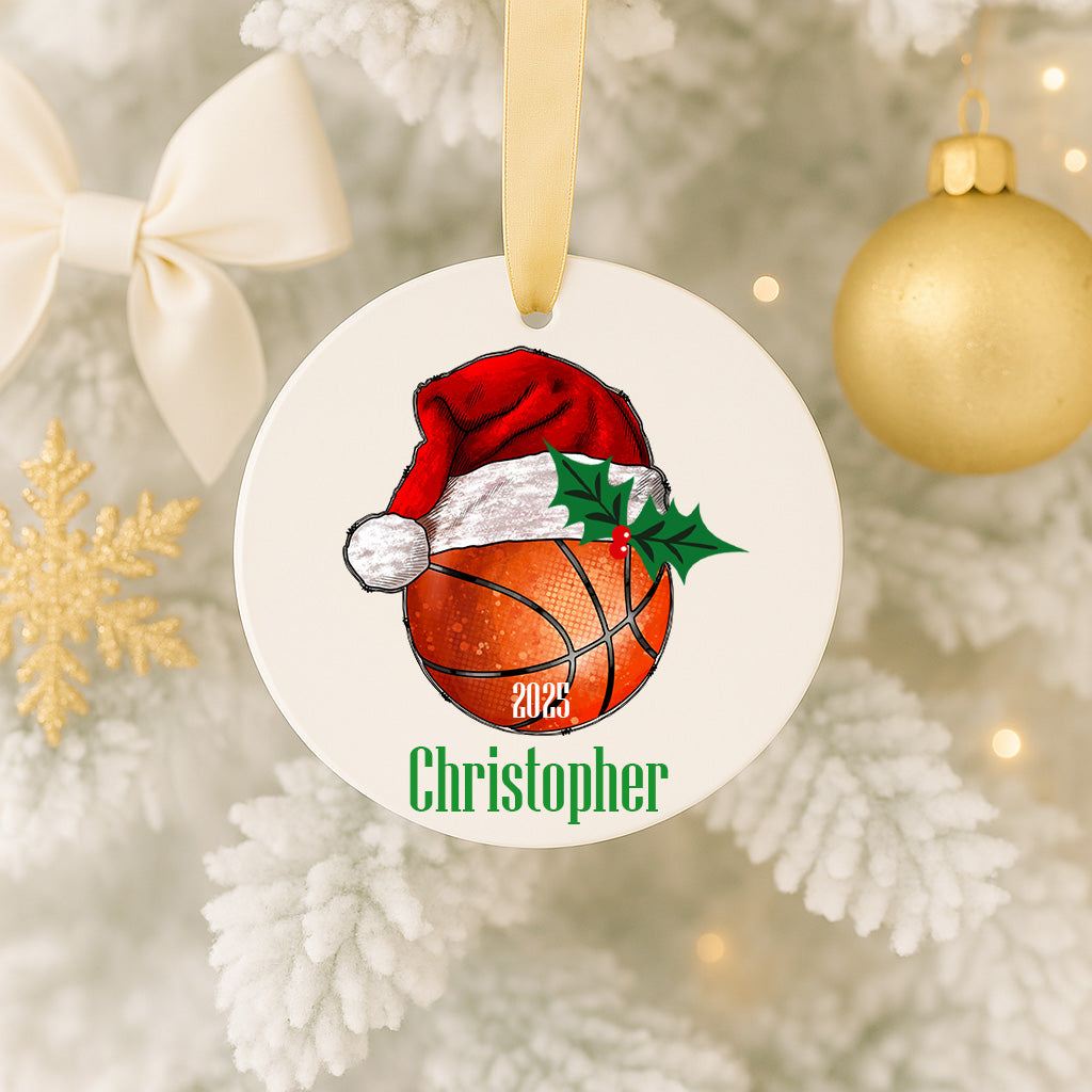 A white ornament with a basketball and a Santa hat on a Christmas tree.