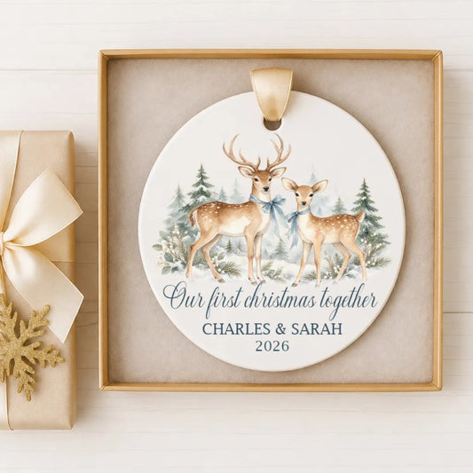 A white ceramic ornament with a deer illustration and the text "Our first Christmas together" and "CHARLES & SARAH 2026" on it, displayed in a gold frame.