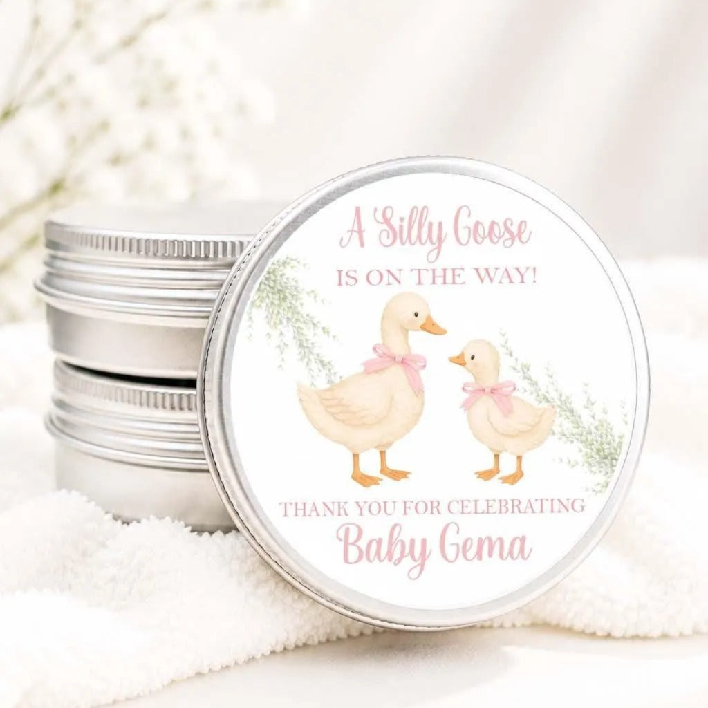 A round tin can with a label featuring illustrations of two ducks and text that reads "A Silly Goose is on the way! Thank you for celebrating Baby Gema".