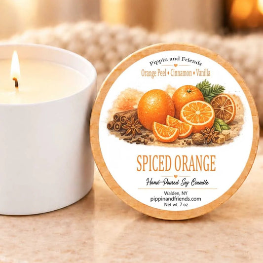 a white candle and a round label with an illustration of oranges and spices, likely representing a scented orange candle.