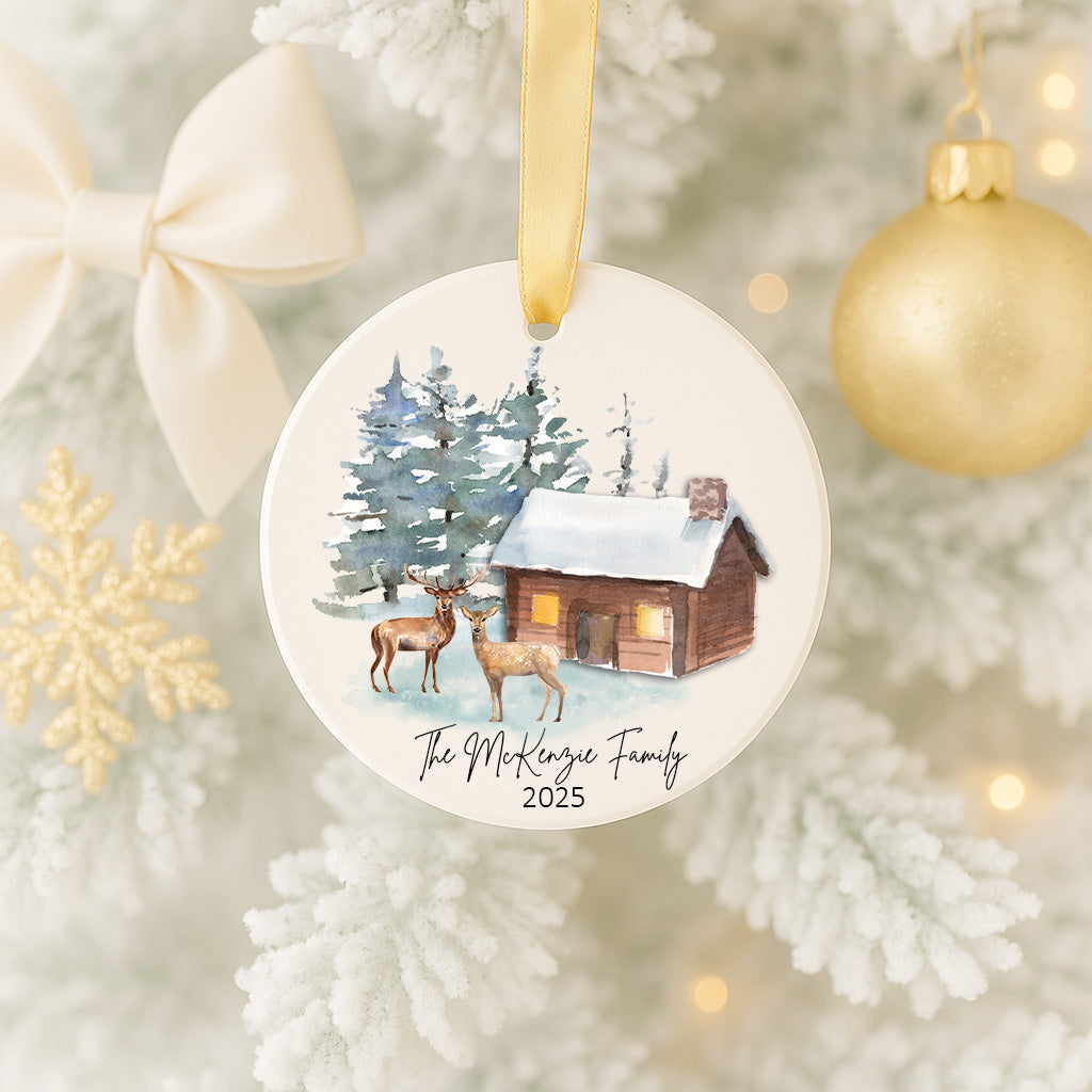 A white Christmas tree decorated with ornaments, including a deer and a cabin, and a gold ornament.