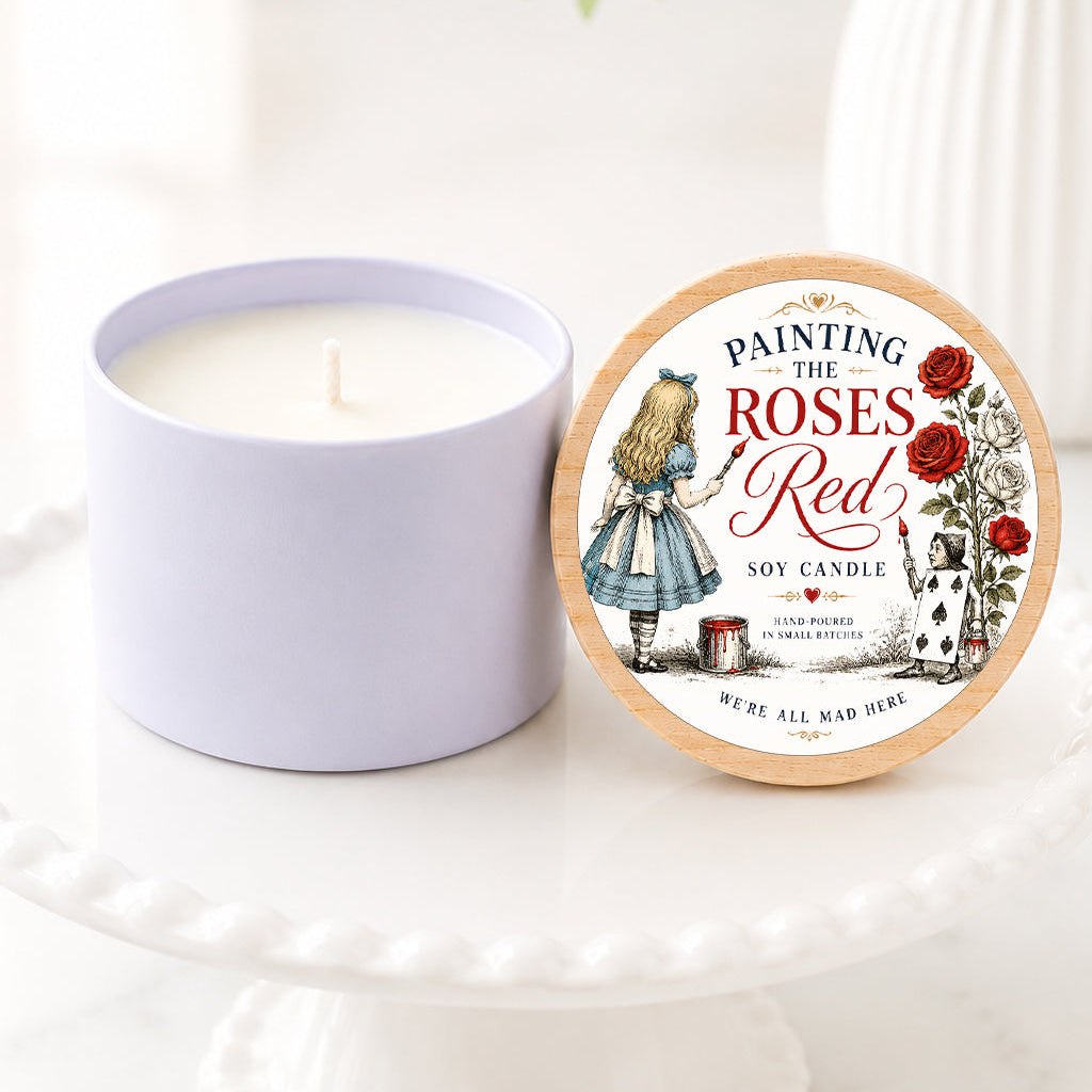 **Alt Text:**

Alice in Wonderland inspired soy candle featuring a “Painting the Roses Red” label with vintage storybook artwork of Alice painting white roses red. The candle is displayed on a white pedestal stand with a natural wood lid, surrounded by soft greenery and white florals in a bright, airy setting. Perfect for book lovers, literary gifts, Wonderland fans, and whimsical home décor.

