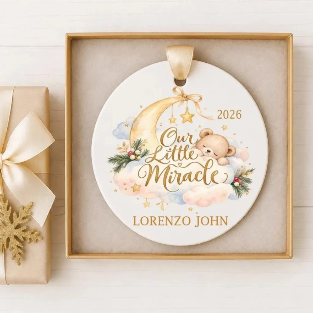 A decorative ornament with a baby bear and a crescent moon, along with the text "Our Little Miracle" and the year "2026". The ornament is displayed in a gold frame.