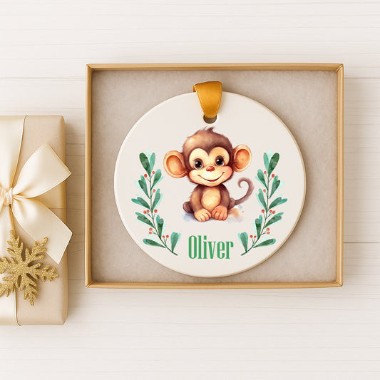 A ceramic ornament featuring a smiling monkey, with the name "Olivier" written on it, displayed in a wooden frame.