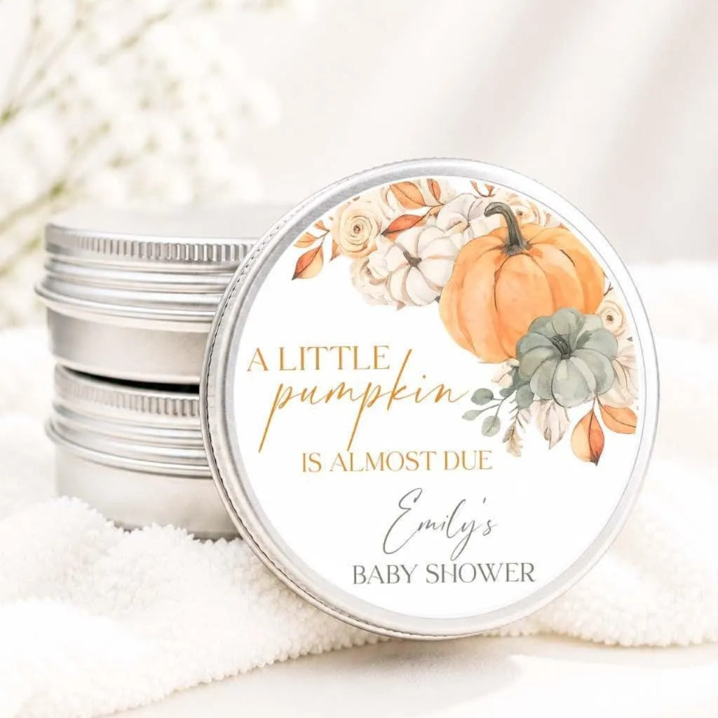 A round tin lid with a label that reads "A little pumpkin is almost due Emily's baby shower" and features an illustration of pumpkins and flowers.