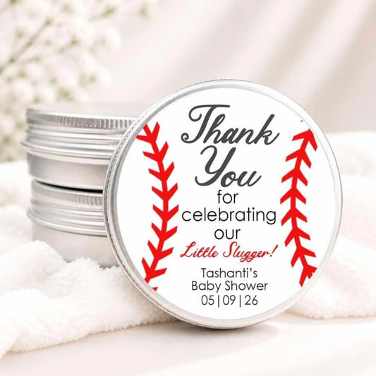 A round tin lid with a label that says "Thank You for celebrating our Little Slugger! Tanishi's Baby Shower 05/09/26"