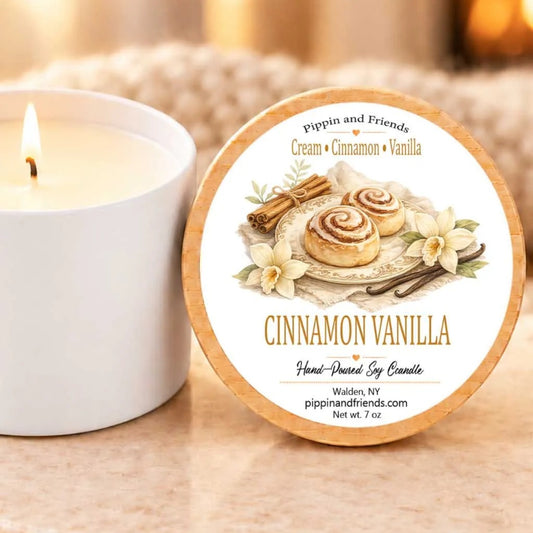 a white candle with a cinnamon and vanilla scent, placed next to a wooden coaster with a cinnamon and vanilla scent label.