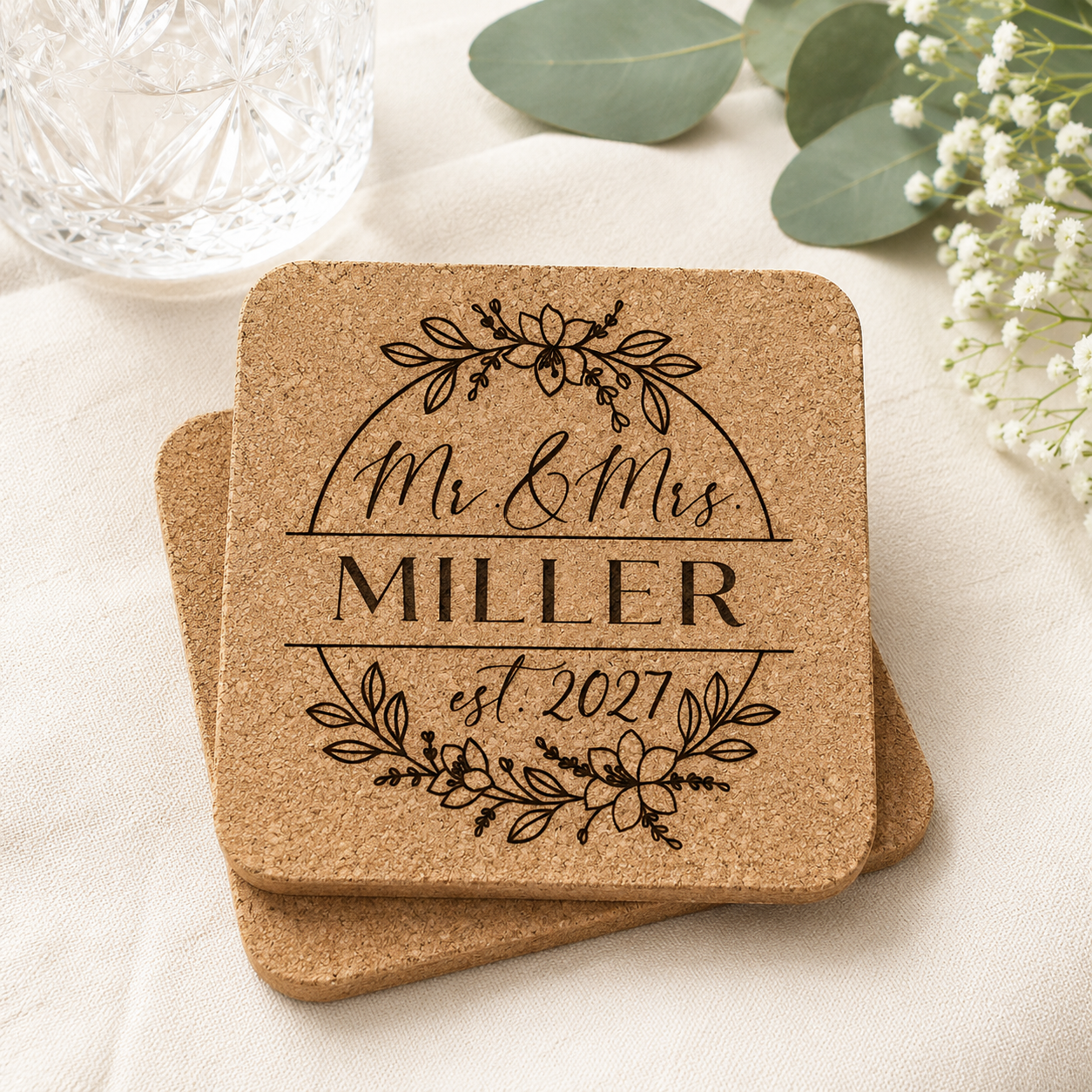 Personalized cork coaster engraved with Mr. and Mrs., custom last name, and established year, displayed in a styled wedding-inspired product mockup.
