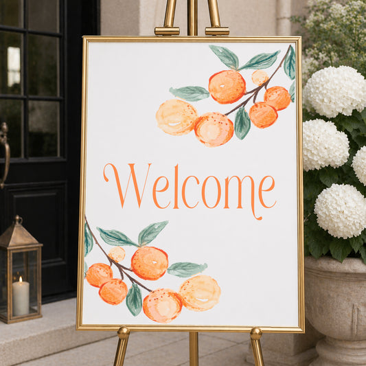 A Little Cutie baby shower welcome sign with citrus design displayed at entrance on easel for event decor.