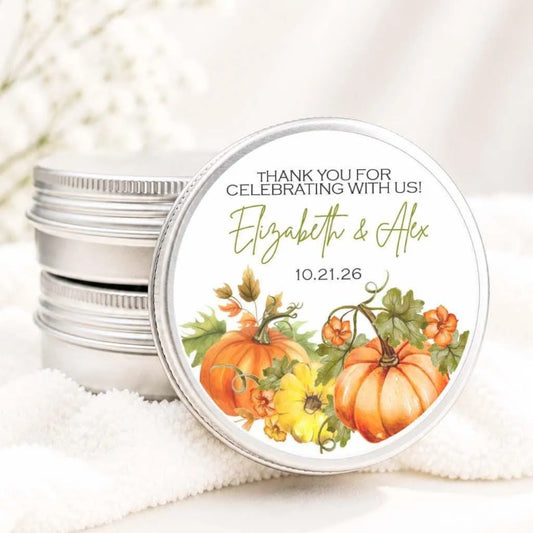 A round tin lid with a decorative design featuring pumpkins and autumn leaves, placed on a white cloth.