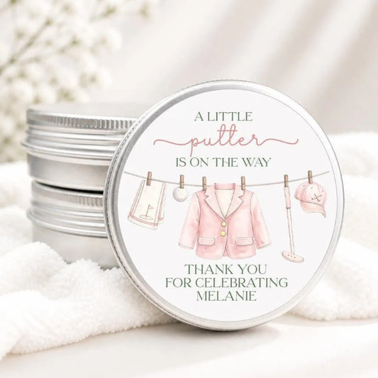 A round tin with a label that says "A little putter is on the way" and "Thank you for celebrating Melanie"