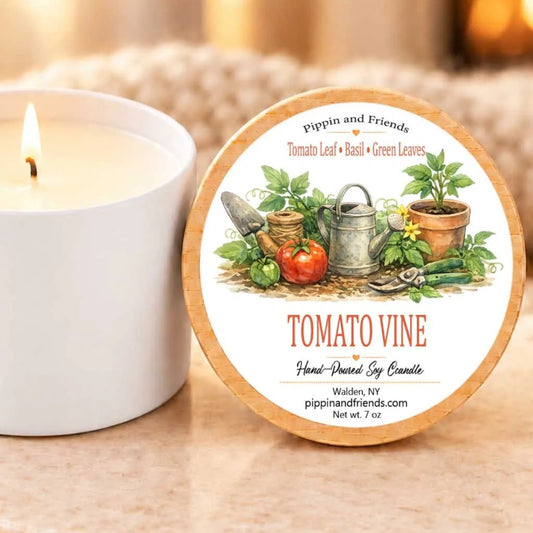 a white candle with a label that reads "Tomato Vine" and "Hand-poured Soy Candle" on a marble coaster.