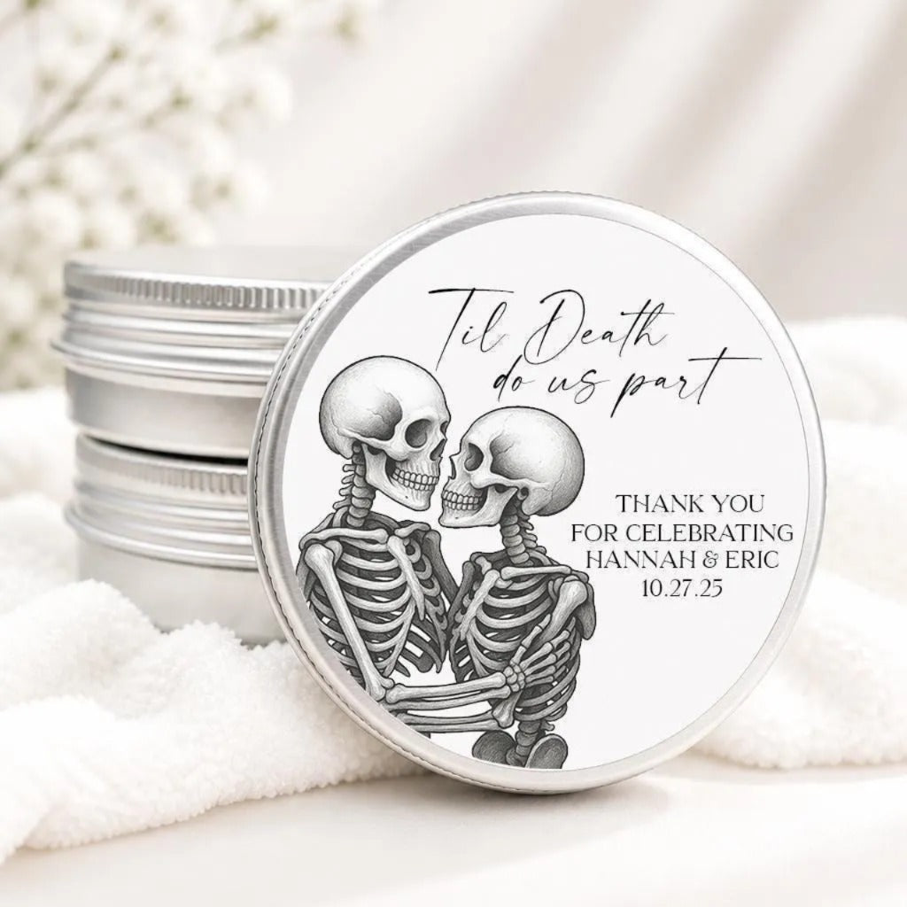 a round tin lid with a black and white illustration of two skeletons embracing each other. The lid has text on it that reads "Til Death do us part" and "Thank you for celebrating Hannah & Eric 10.27.25".