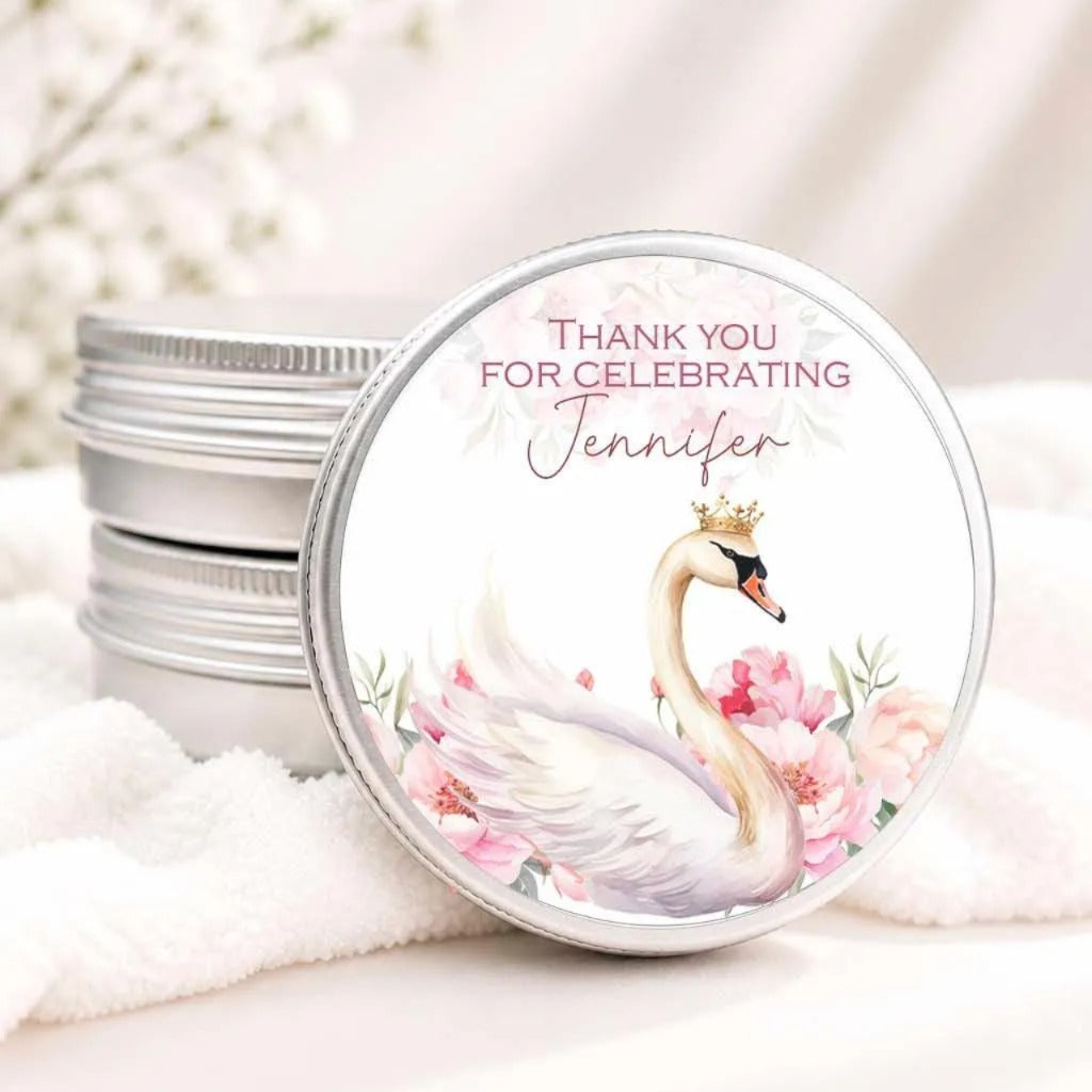 A round tin lid with a decorative image of a swan wearing a crown, surrounded by pink flowers. The lid has a message that says "Thank you for celebrating Jennifer".