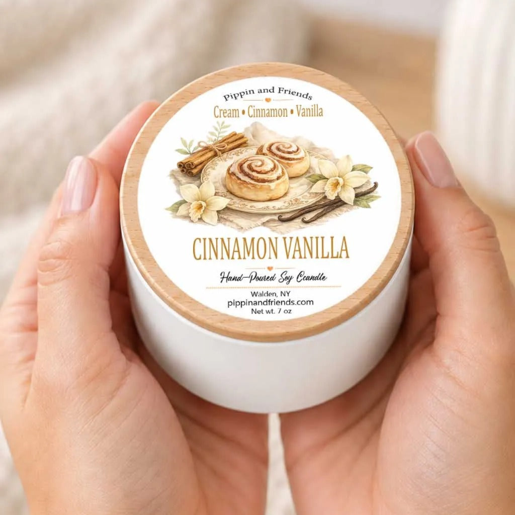 A person's hands holding a white container with a label that features an illustration of cinnamon buns and other cinnamon-related items.
