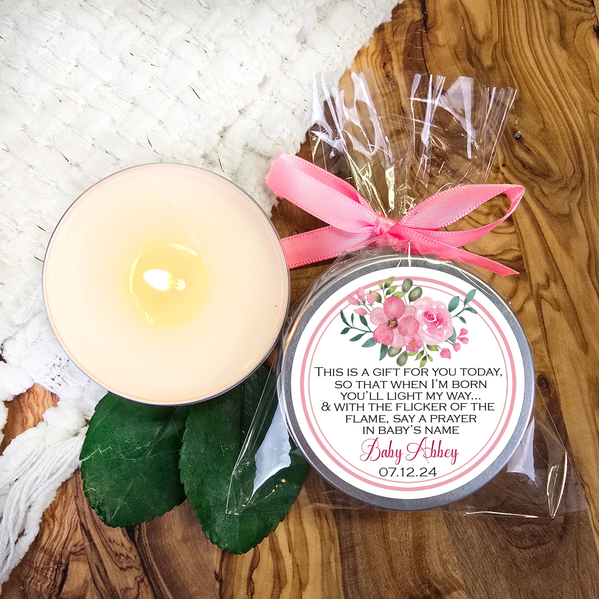 a candle with a pink ribbon next to it