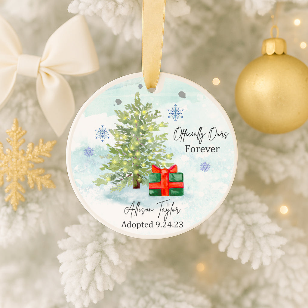 A Christmas ornament with a tree and a gift, hanging on a tree.