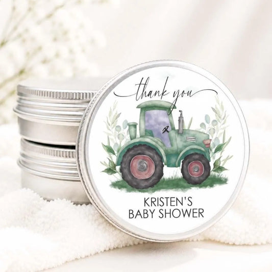 A round tin can with a green tractor illustration and a "Thank you" message, placed on a white cloth.