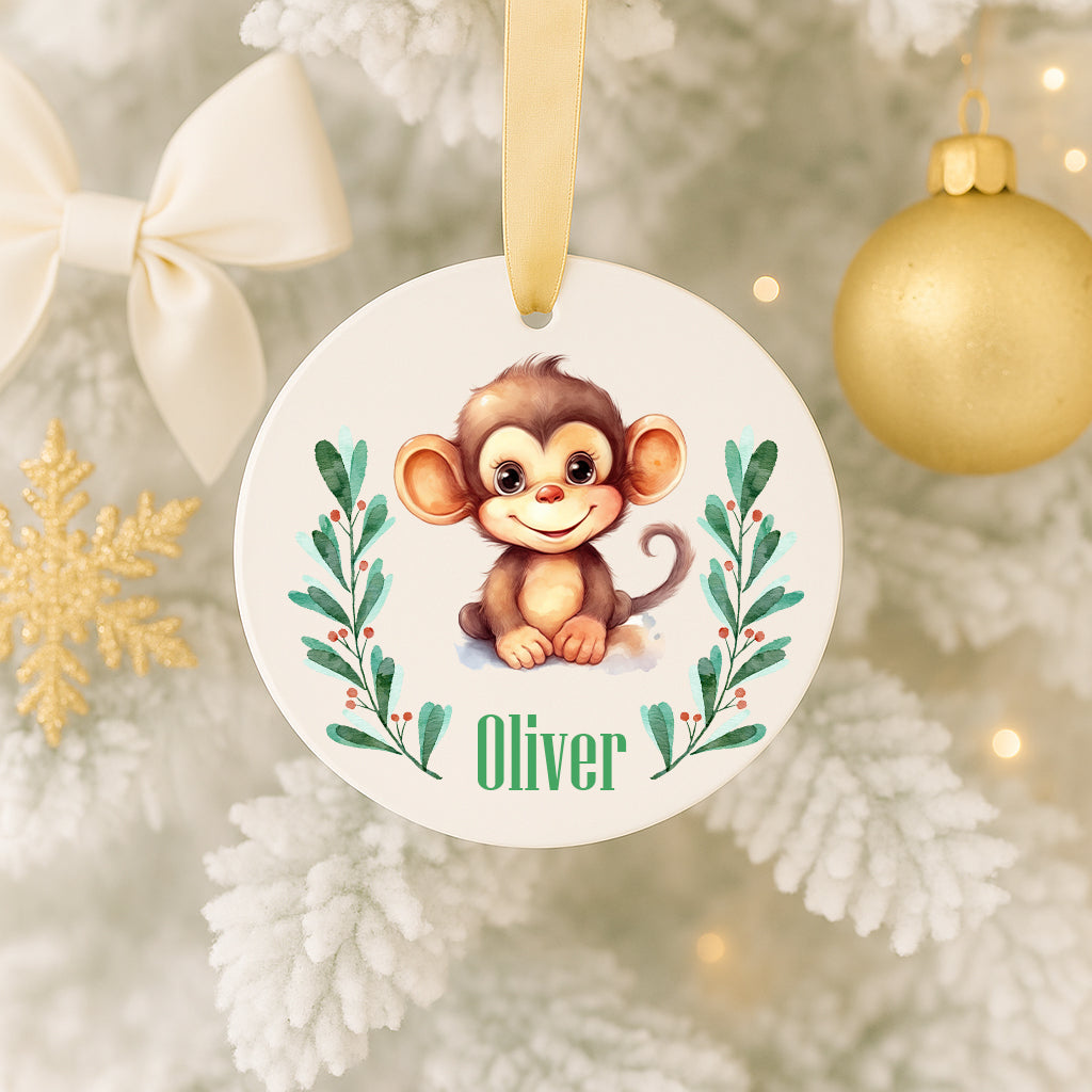 A round ornament featuring a smiling monkey, surrounded by green leaves and a ribbon, hanging on a Christmas tree.