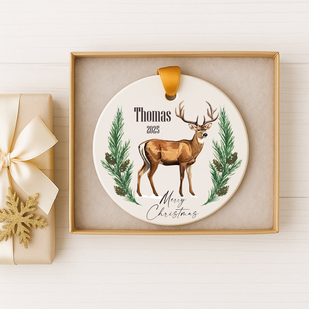 A white ceramic ornament with a deer illustration and the text "Thomas 2020" is displayed in a gold frame.