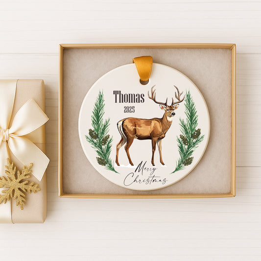A white ceramic ornament with a deer illustration and the text "Thomas 2020" is displayed in a gold frame.