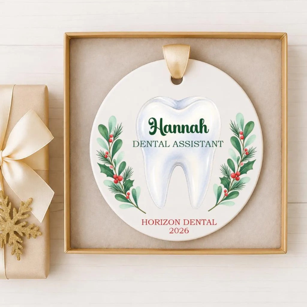A white ceramic ornament with a tooth design and holiday-themed decorations, placed in a wooden frame.