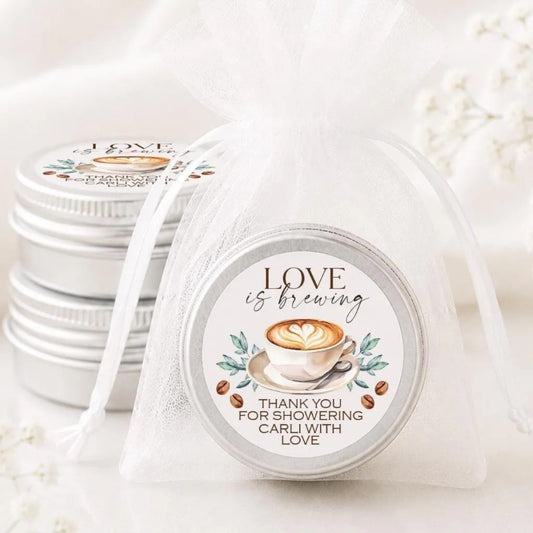 a close-up of a tin can with a label that reads "LOVE is brewing" and "Thank you for showering CARLI with LOVE". The can is placed on a white surface, and there are other similar cans visible in the background.