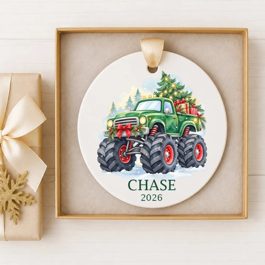 A white ceramic ornament with a green monster truck and a Christmas tree, hanging on a wall.