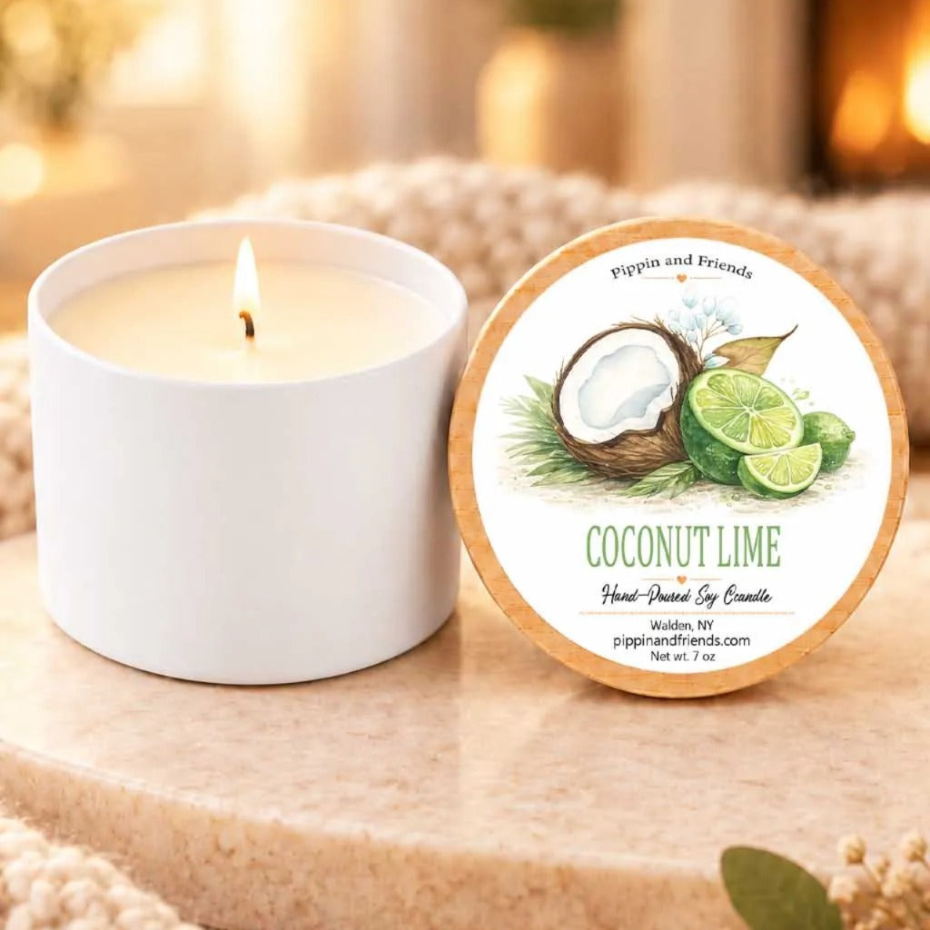 a white candle labeled "Coconut Lime" next to a white candle holder, both sitting on a wooden surface.