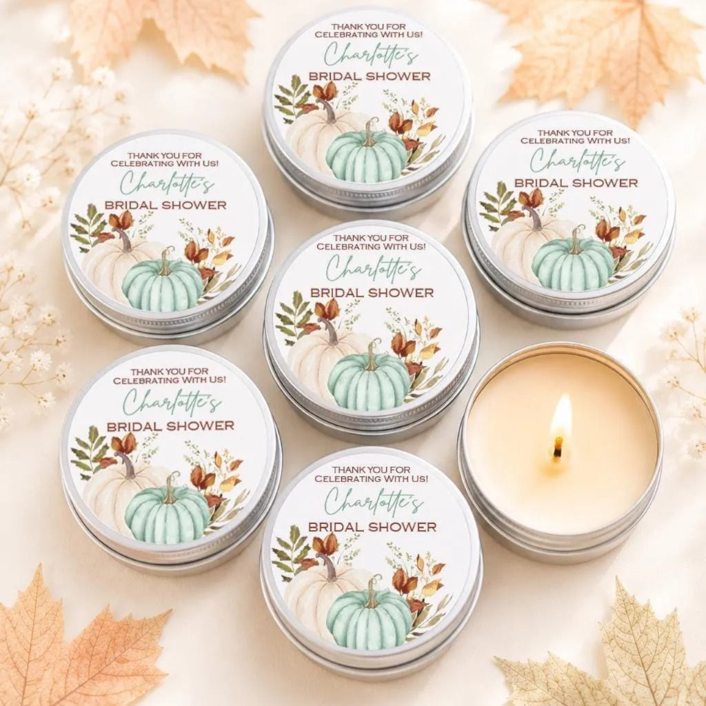 six silver tins arranged on a table, each with a label that reads "Thank you for celebrating with us! Charlotte's BRIDAL SHOWER". The tins are surrounded by autumn leaves, creating a festive and seasonal atmosphere.