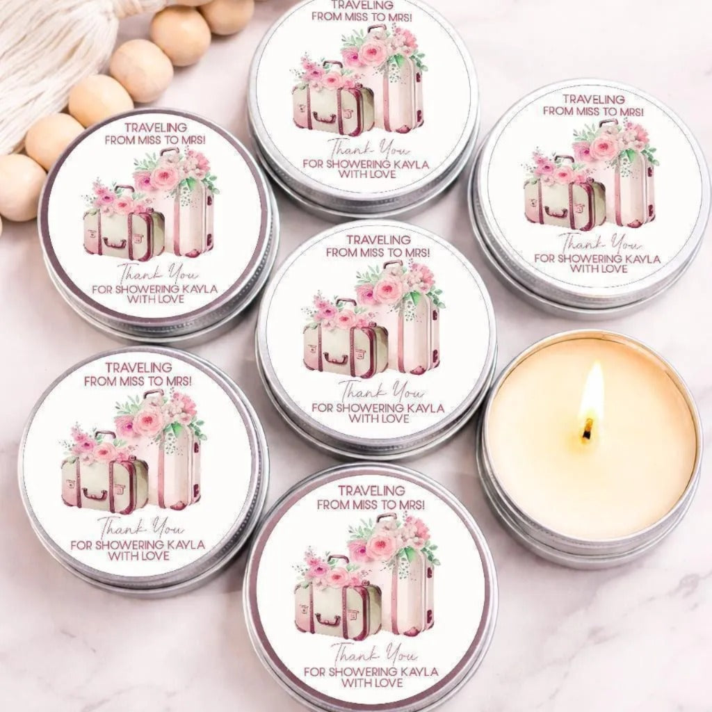 a collection of round tin containers with floral designs, each containing a candle and a message of gratitude. The containers are arranged on a marble surface, with a lit candle in the center.