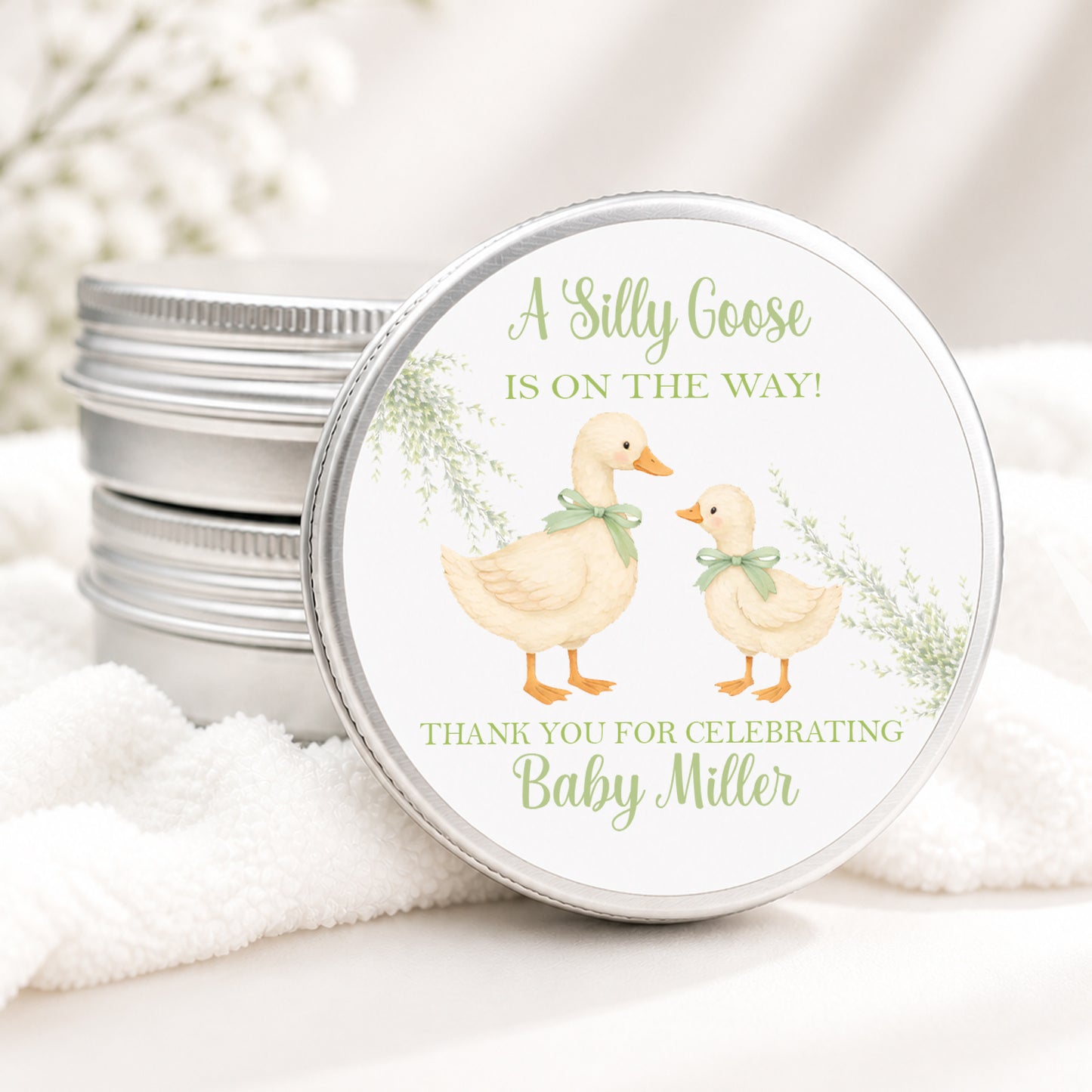 Personalized Silly Goose baby shower candle favor in a silver tin featuring a sweet mother and baby goose with sage green bows, soft greenery, and custom baby shower details, displayed on a soft white background.