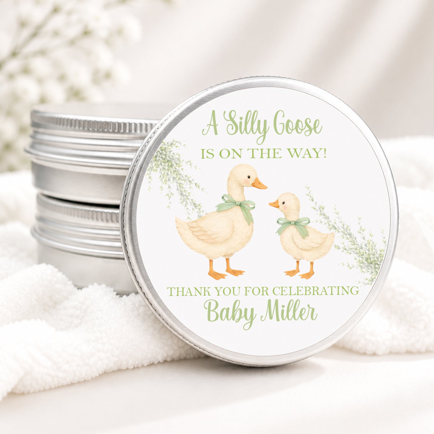 Personalized Silly Goose baby shower candle favor in a silver tin featuring a sweet mother and baby goose with sage green bows, soft greenery, and custom baby shower details, displayed on a soft white background.