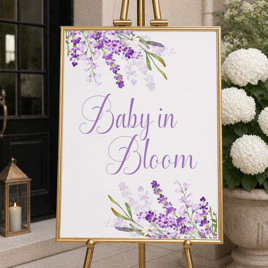 Lavender baby in bloom welcome sign with purple floral design displayed on easel for baby shower entrance decor.