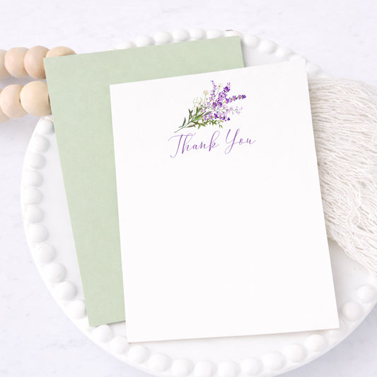 Lavender thank you cards with purple floral design and envelopes, arranged for bridal shower or wedding stationery.