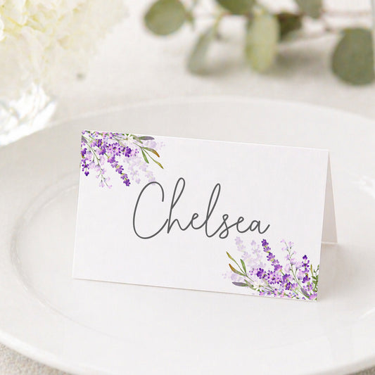 Lavender place cards with purple floral design displayed on table for wedding or bridal shower seating arrangement.