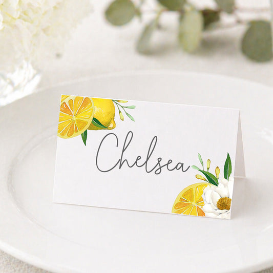 Amalfi Coast lemon place card with guest name “Chelsea” displayed on plate, Mediterranean wedding table setting with citrus design.