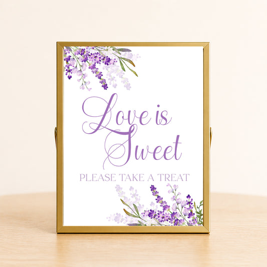 Lavender love is sweet sign with purple floral design displayed on dessert table for bridal shower or wedding decor.
