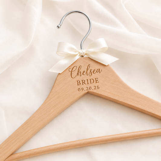 Personalized wooden bridal hanger engraved with bride's name, wedding title, and date, featuring a satin bow and silver hook for wedding dress display.