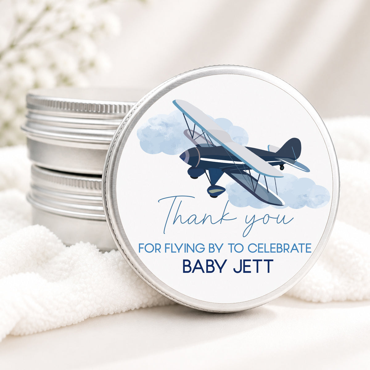 Personalized airplane baby shower candle favor in a silver tin featuring a vintage airplane design and custom baby shower wording.