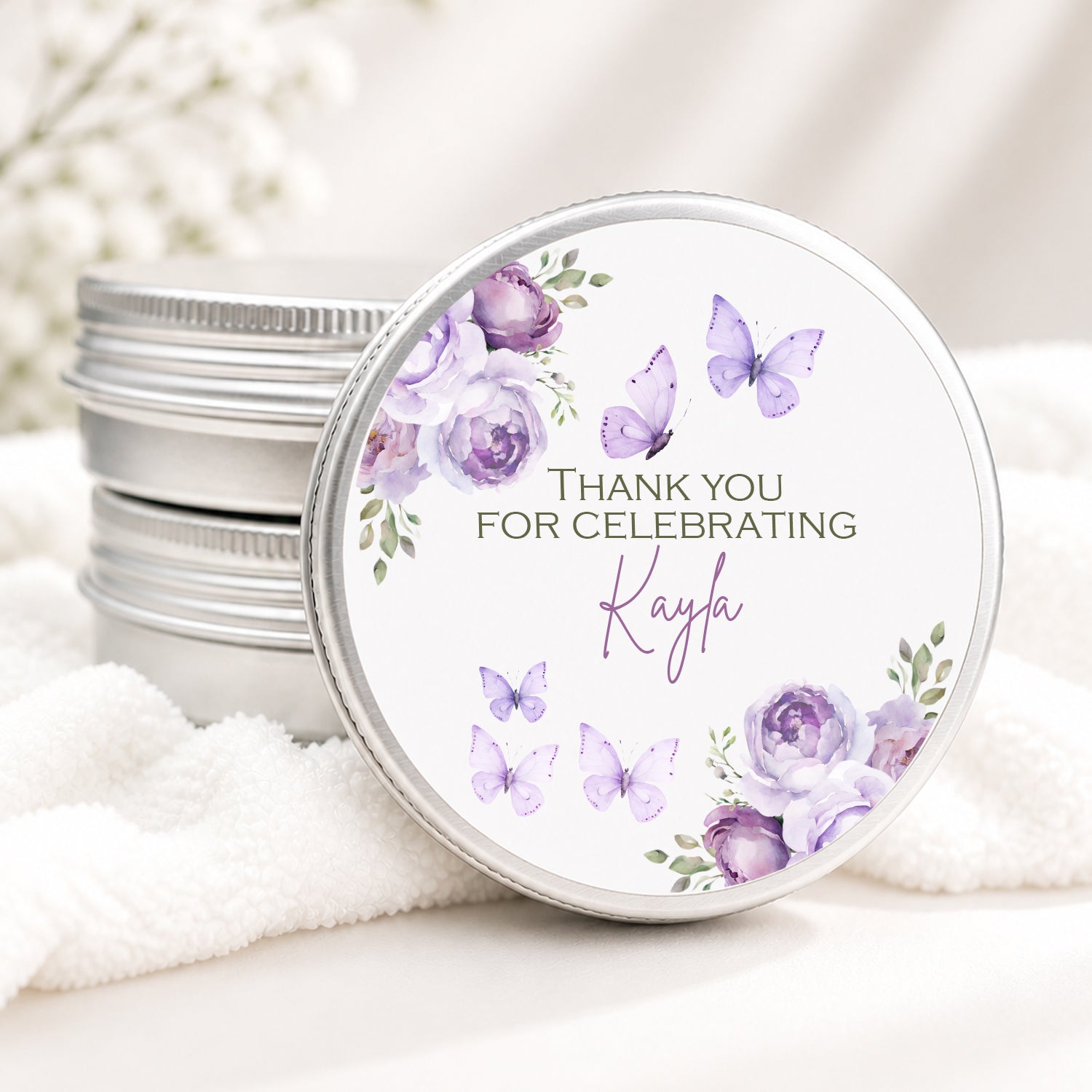 Personalized butterfly candle favor in a silver tin featuring lavender watercolor flowers, purple butterflies, and custom event details, displayed on a soft white background.
