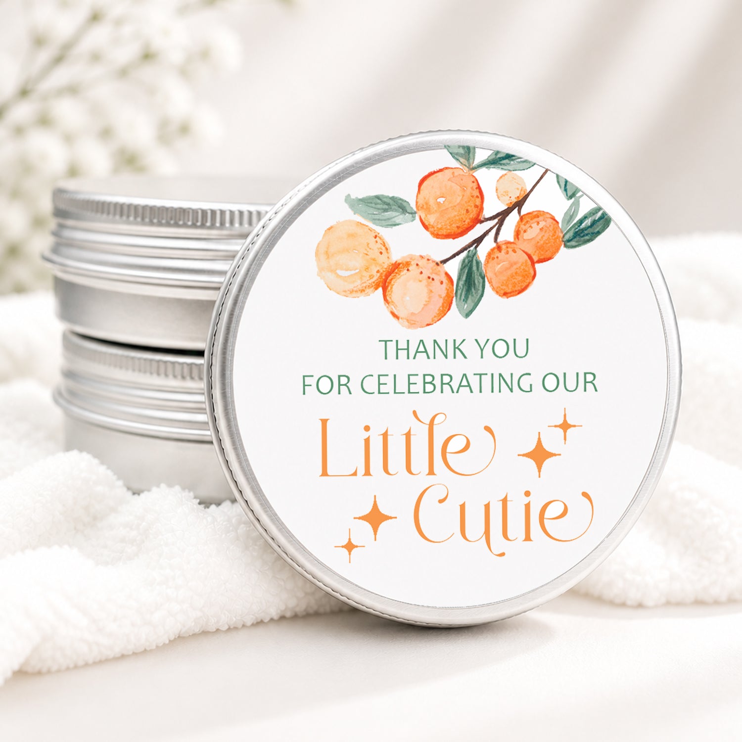 Little Cutie baby shower candle favor in a silver tin featuring watercolor oranges, greenery, and a sweet citrus-themed design displayed on a wooden surface.
