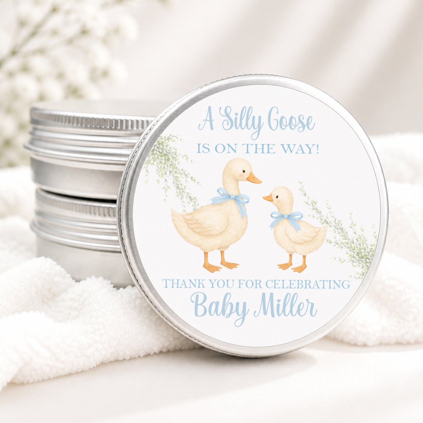 Personalized Silly Goose baby shower candle favor in a silver tin featuring a sweet mother and baby goose with blue bows, soft greenery, and custom baby shower details, displayed on a soft white background.