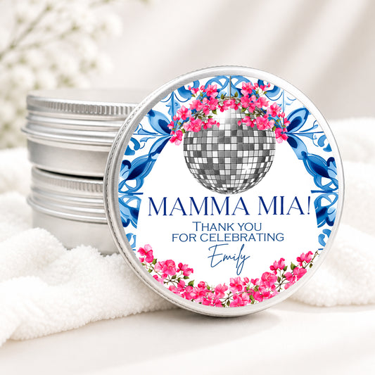 Personalized Mamma Mia themed candle favor in a silver tin featuring a disco ball, pink bougainvillea flowers, blue Mediterranean tile design, and custom event details on a soft white background.
