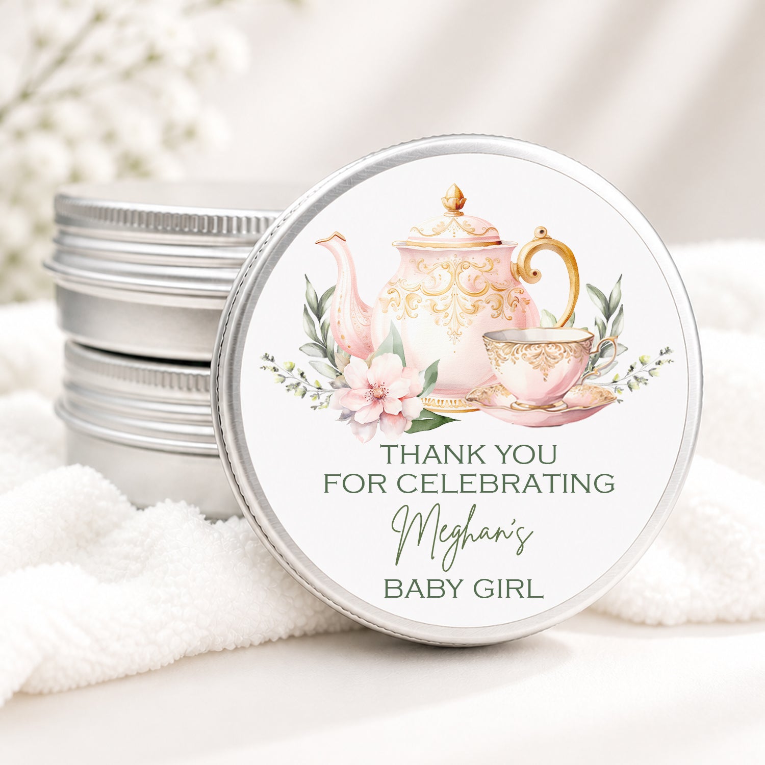 Personalized tea party baby shower candle favor in a silver tin featuring an elegant pink and gold teapot, teacup, floral accents, and custom baby shower details, displayed on a soft white background.