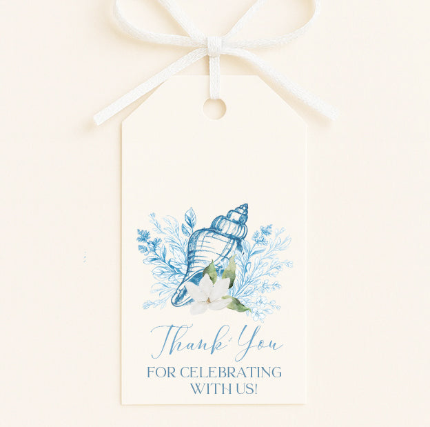 A white tag with a bow, featuring a blue and white seashell and flowers, along with the text "Thank You for Celebrating With Us!"